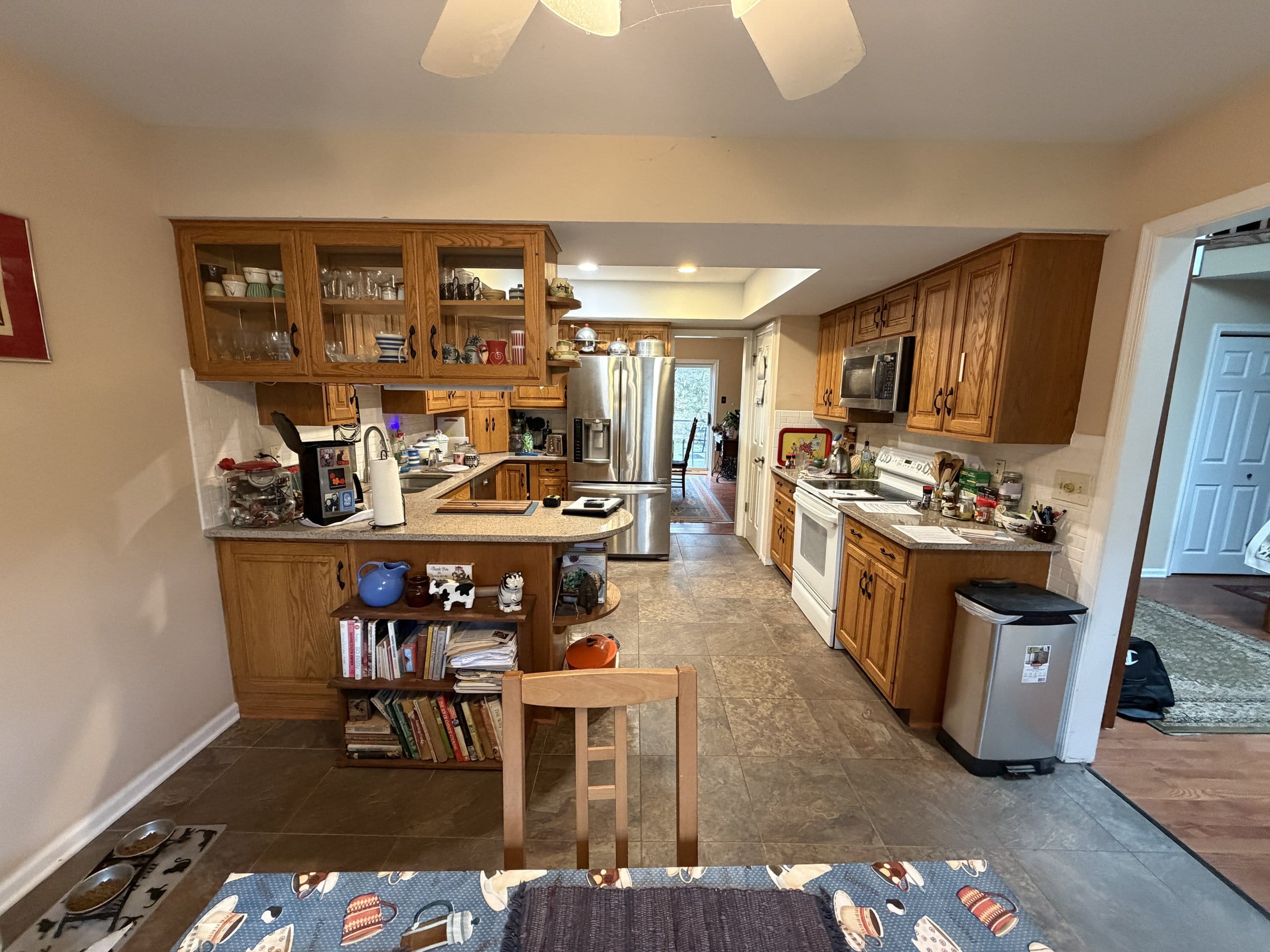 West Chester kitchen before the refresh with honey-oak cabinets, a peninsula with open shelving, and dated beige countertops