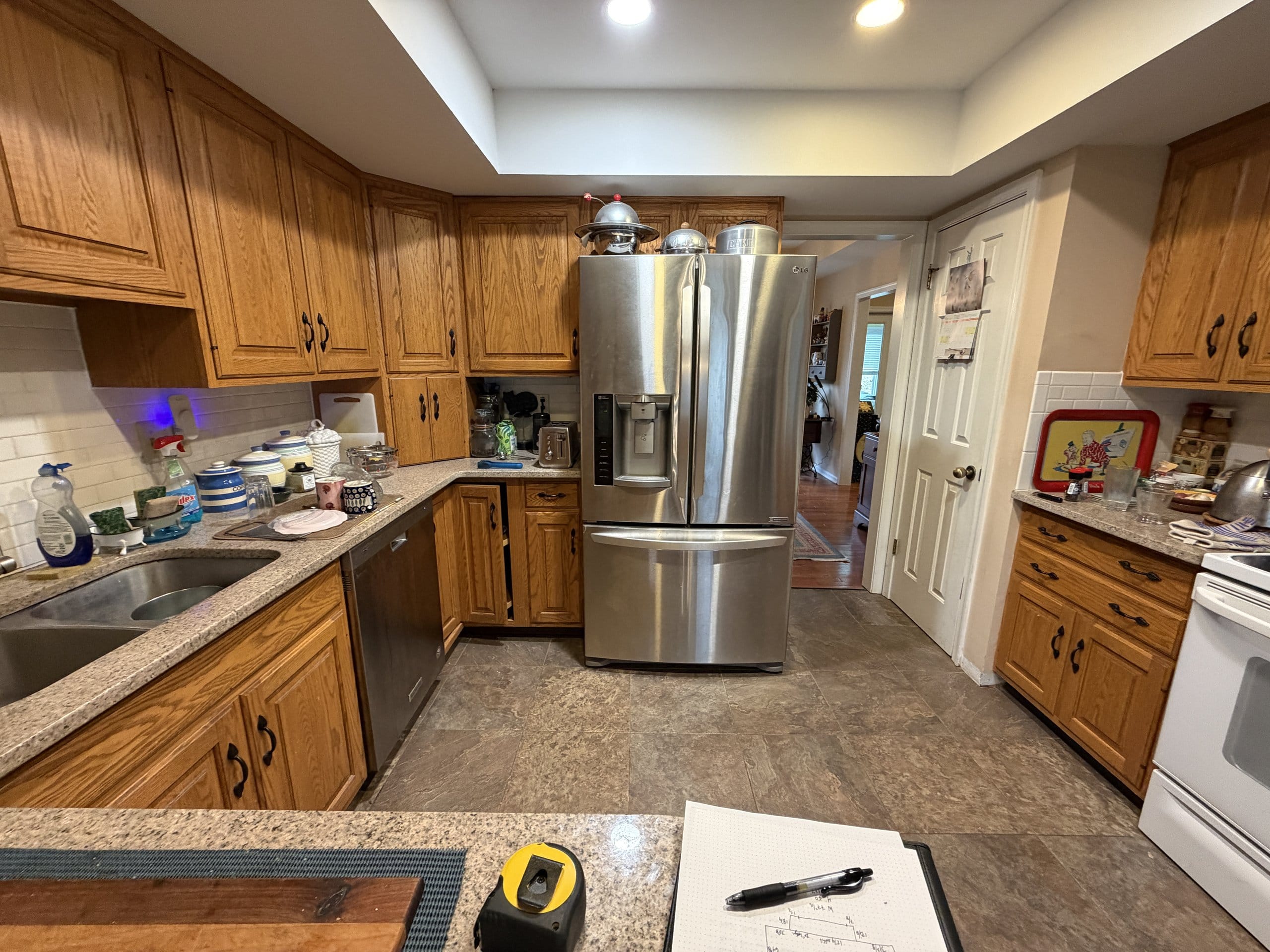 Before the refresh: oak cabinets and beige countertops around a stainless refrigerator